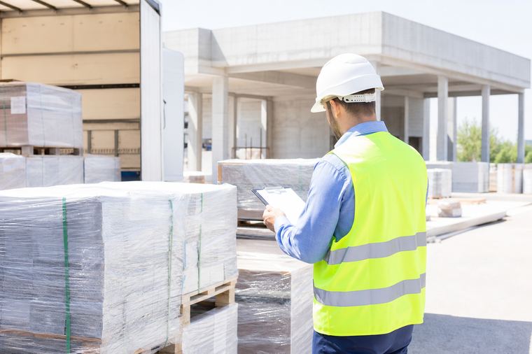 Una parete costruita con pallet di legno accatastati, assi chiare e chiodi ben visibili.