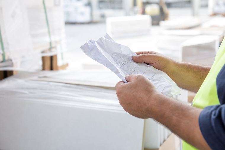 Le mani di una persona reggono un foglio stampato in bianco e nero, ripreso da vicino.